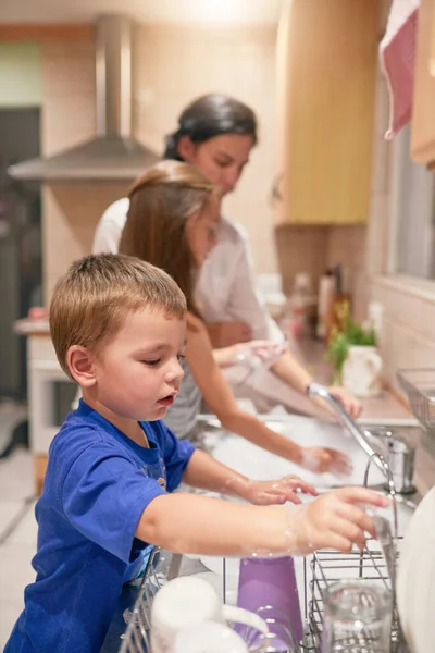 Viele Hände am Werk. Aufnahme eines kleinen Jungen beim Geschirrspülen mit seiner Familie an einer Spüle. — Stockfoto