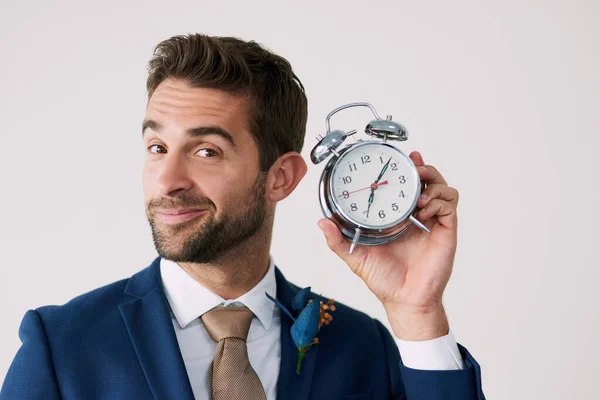 L'attesa è finita. Studio foto di un bel giovane sposo che tiene un orologio su uno sfondo grigio. — Foto Stock