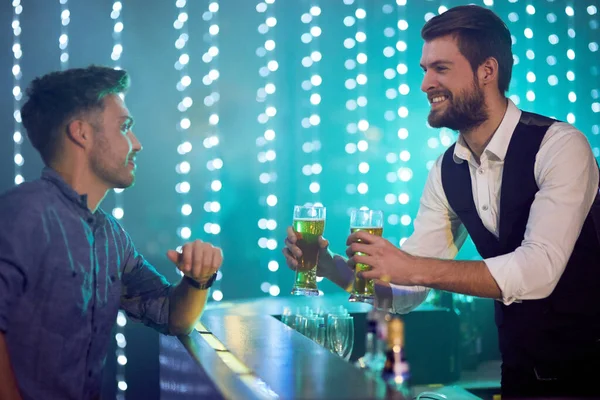 Dos cervezas listas. Foto recortada de un camarero sirviendo bebidas a un hombre en un club nocturno. — Foto de Stock