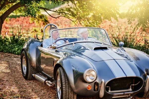 Exploring the outdoors in style. Shot of a happy senior couple enjoying a roadtrip in a convertible. — Stock Photo, Image