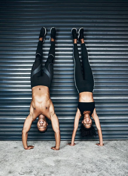 Ven con nosotros. Foto de una joven pareja deportiva haciendo handstands sobre un fondo gris. —  Fotos de Stock