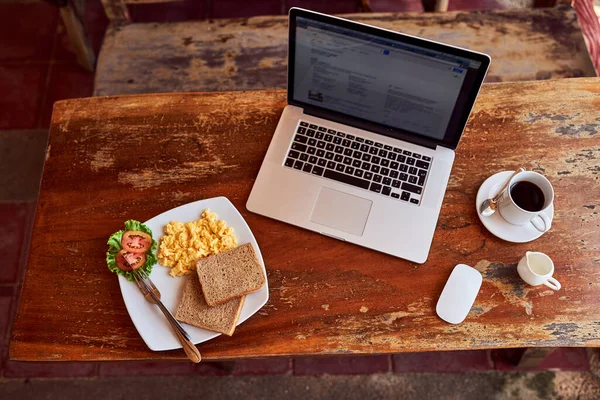 朝食の接続。ノートパソコンの高角度ショットとテーブルの上に焼きたての朝食. — ストック写真