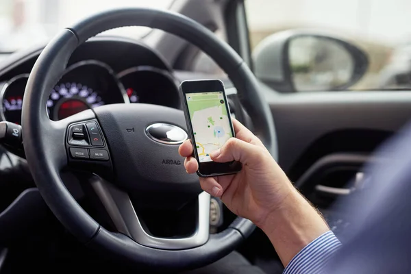 Låt din GPS vägleda dig. Närbild bild av en förare i en bil med hjälp av en mobiltelefon för att hitta vägbeskrivning. — Stockfoto