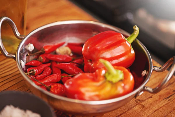 Certains aiment ça chaud. Tournage d'une casserole remplie de poivrons rouges et de piments sur une table. — Photo