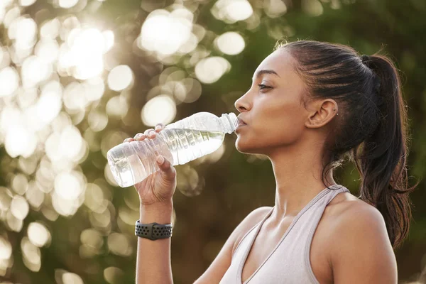 Machen Sie Pausen, wenn Sie neue Energie tanken möchten. Aufnahme einer sportlichen jungen Frau, die beim Sport im Freien Wasser trinkt. — Stockfoto