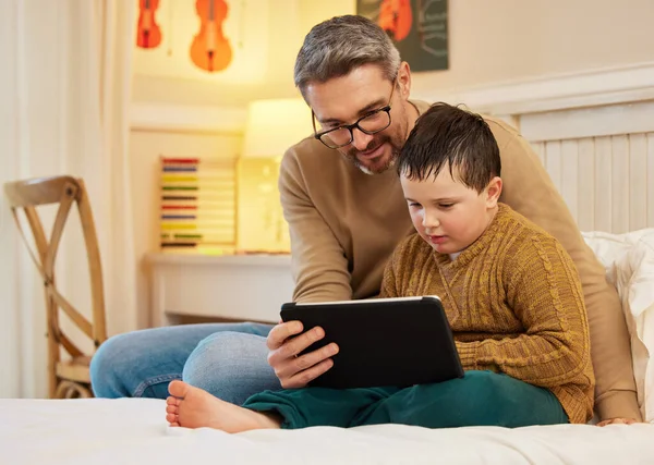 Ti lascio guardare un ultimo episodio prima di andare a letto. Girato di un padre e un figlio utilizzando un tablet digitale insieme in una camera da letto a casa. — Foto Stock