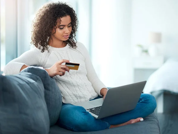 Teknolojinin rahatlığı sayesinde. Evde bilgisayarını kullanırken kredi kartını tutan genç bir kadının fotoğrafı.. — Stok fotoğraf