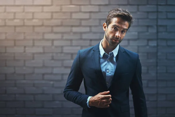 Vístete para el éxito y luego sal a buscarlo. Retrato de un joven hombre de negocios guapo de pie contra una pared de facebrick gris. —  Fotos de Stock