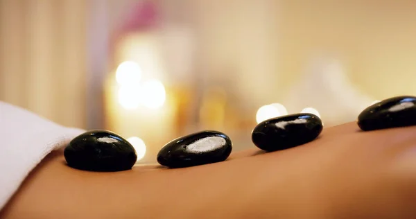 The hotter the stone, the better the relief. Shot of an unrecognizable woman getting a hot stone massage at a beauty spa. — Stock Photo, Image
