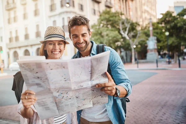 Entrambi amiamo esplorare i nostri dintorni. Scatto di una coppia felice che utilizza una mappa mentre esplora una città straniera. — Foto Stock