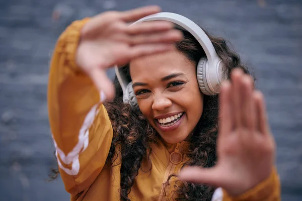 La buena música es lo que me hace feliz. Recortado disparo de una hermosa mujer joven con auriculares mientras estaba de pie fuera. — Foto de Stock