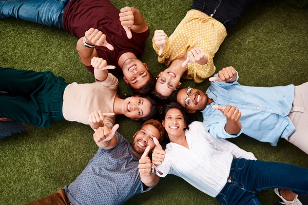 Esperamos que muchas cosas buenas te lleguen. Retrato de un grupo de jóvenes creativos mostrando los pulgares hacia arriba mientras yacen juntos en un grupo. — Foto de Stock