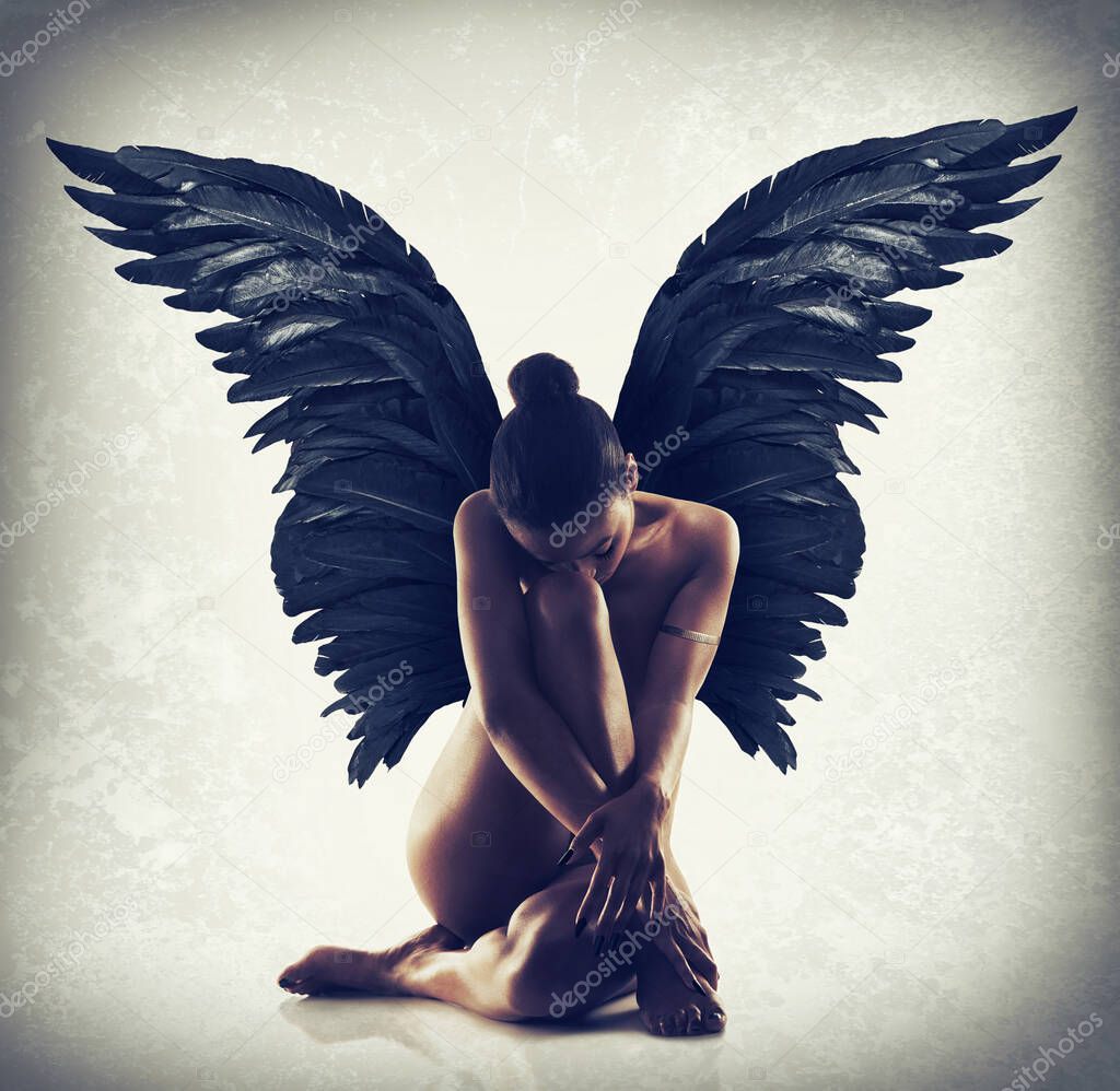 Poise in the stillness. Shot of of naked woman with wings spreading out behind her back.