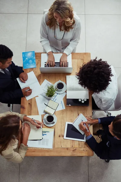 Er is hard werk voor nodig om succes te boeken. Hoge hoek foto van een groep van zakenmensen die een vergadering in een kantoor. — Stockfoto