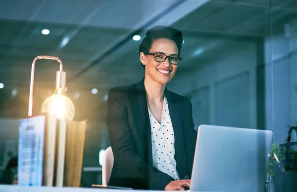 Alleen ambitie brengt je naar de top. Portret van een zelfverzekerde zakenvrouw die 's nachts op een laptop in een kantoor werkt. — Stockfoto