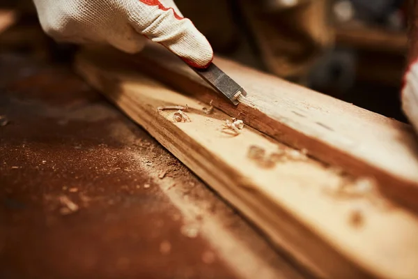 Cet outil fait des merveilles. Gros plan d'un menuisier méconnaissable classant un morceau de bois à l'intérieur d'un atelier la nuit. — Photo