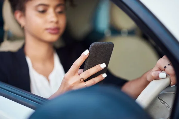 Znajdę najbliższą stację. Przycięte ujęcie atrakcyjnej młodej bizneswoman korzystającej ze smartfona podczas jazdy samochodem. — Zdjęcie stockowe
