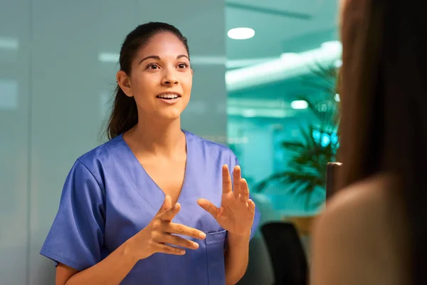 Spiegando i pro e i contro della copertura medica. Girato di una giovane infermiera che discute una procedura con il suo paziente in clinica. — Foto Stock