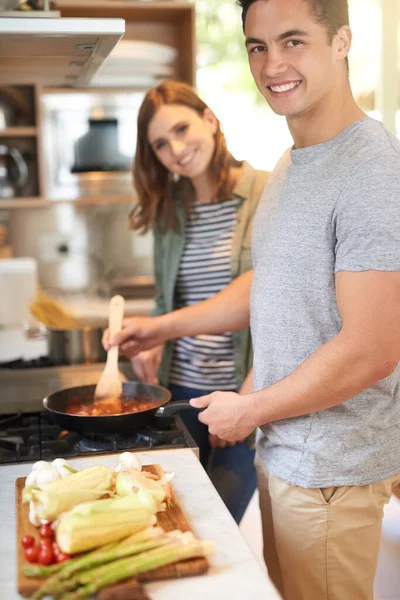 Juntos es un lugar maravilloso para estar. Retrato de una feliz pareja joven cocinando una comida juntos en su cocina. — Foto de Stock