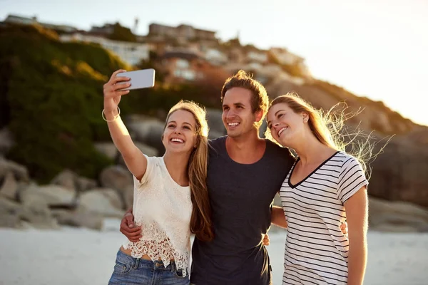 Selfies er digitale minner. Skutt av tre venner som tok en selfie på stranden. – stockfoto