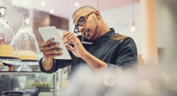 2 시에 회의할 자리가 있어요. 한 남자가 커피숍에서 디지털 태블릿을 사용하면서 핸드폰으로 이야기하는 모습을 찍은 사진. — 스톡 사진