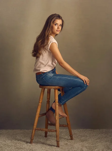 如果你想成为一个完美组合的烂摊子。摄影棚拍摄的是一个漂亮的年轻女子坐在一张平平的背景的凳子上. — 图库照片