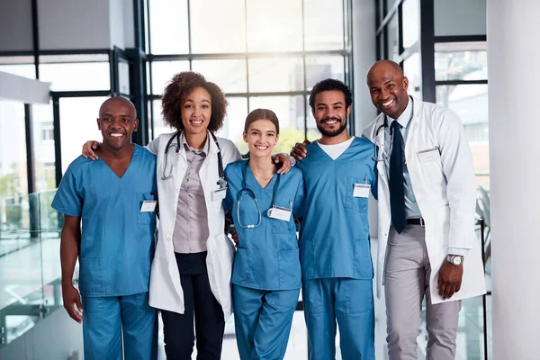 Ils prendront soin de vos besoins médicaux. Portrait d'un groupe joyeux de médecins debout les bras les uns autour des autres à l'intérieur d'un hôpital pendant la journée. — Photo