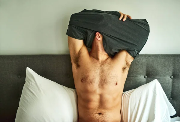 A ficar confortável para a cama. Tiro cortado de um homem irreconhecível despir-se em sua cama em casa. — Fotografia de Stock