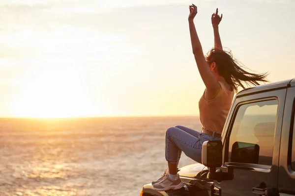 Remerciez les dons de l'univers. Prise de vue d'une jeune femme célébrant une victoire personnelle en regardant le coucher de soleil sur la plage. — Photo