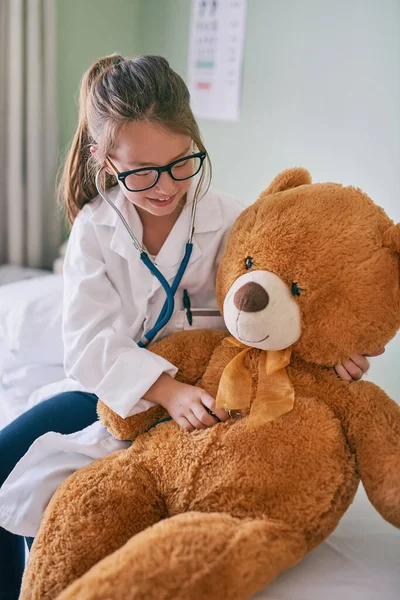 Dein Herz ist gesund und voller Liebe. Aufnahme eines kleinen Mädchens, das sich als Arzt ausgibt, während es seinen Teddybär untersucht. — Stockfoto