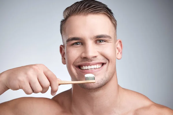 A szájhigiénia elengedhetetlen. Stúdió portré egy vonzó fiatalember mossa fogát a szürke háttér. — Stock Fotó