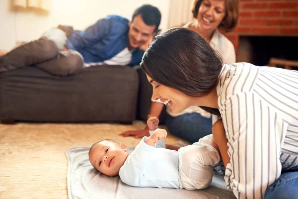 Elle adore son petit garçon. Plan recadré d'une jeune femme séduisante et de son bébé garçon qui se lient à la maison avec la famille en arrière-plan. — Photo