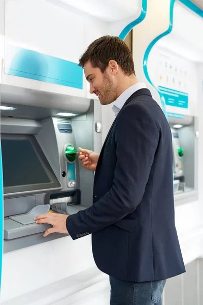 Rychle vybírám hotovost. Vystřižený snímek mladého podnikatele, který provádí transakci v bankomatu. — Stock fotografie