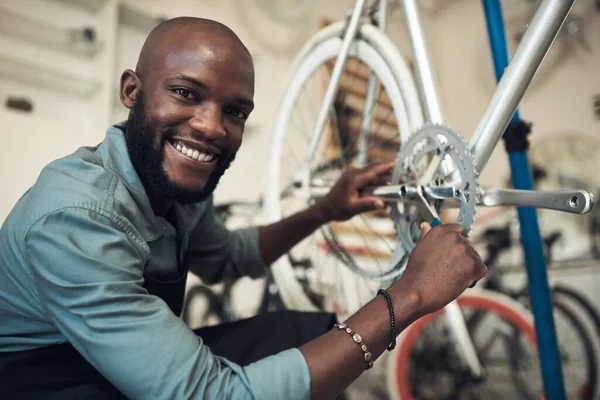 拍了一个英俊的年轻人蹲在他的店里修理自行车轮 — 图库照片