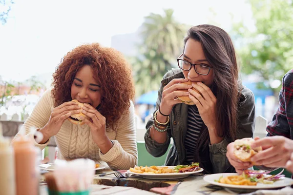 Cropped shot of a friends eating burgers outdoors.