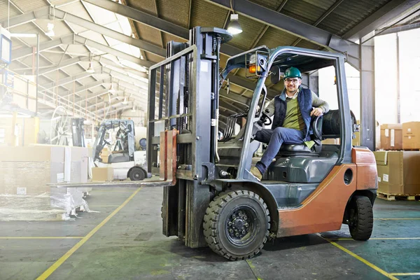 Portrait of driver in a forklift on the factory floor.