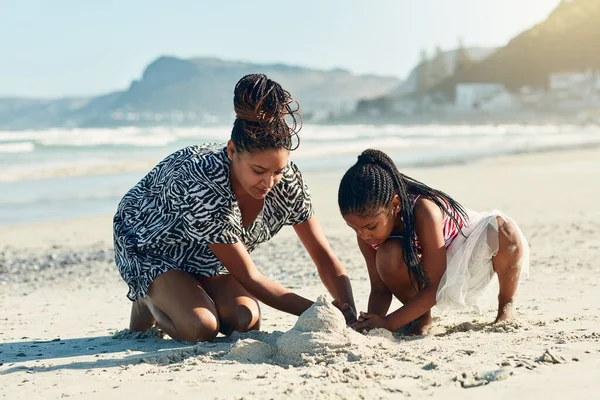 ビーチで一緒に砂の城を建てる母親と彼女の娘のショット — ストック写真