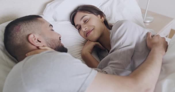 사랑하는 부부가 침대에 키스하는 아침입니다 아내는 자기들의 현대식 침실에서 침대에 — 비디오