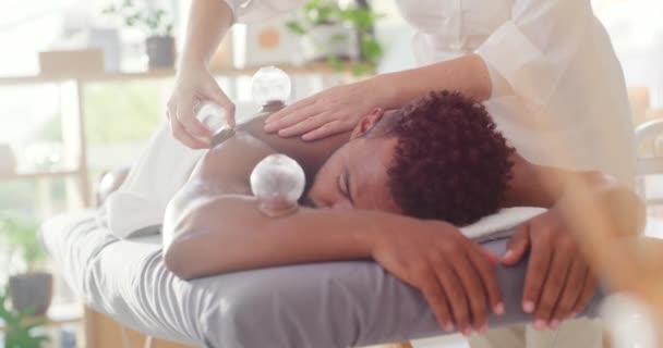 Mladý míšenec si užívá relaxační a terapeutickou masáž zad s vakuovým šálkem v lázních. Kosmetický terapeut léčení bolesti těla s přísavkou terapie k odstranění toxinů.