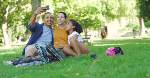 年轻的无忧无虑的家庭坐在公园里自拍 一个快乐的拉丁男人和他的小女儿和妻子在花园里合影 有趣的是 父母把时间花在外面陪孩子 — 图库视频影像