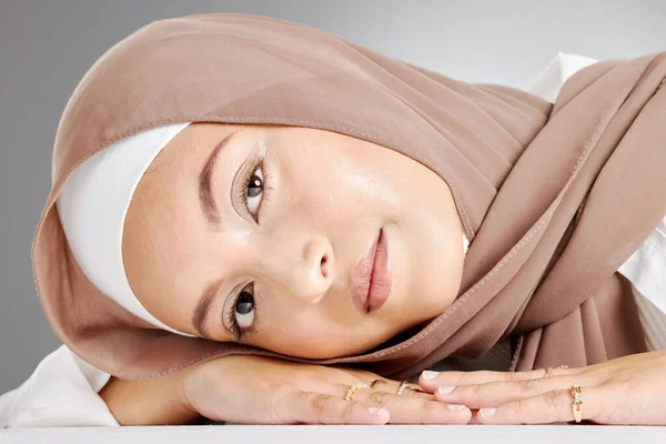 灰色の背景に横たわる茶色のスカーフを身に着けている1つの美しい若いイスラム教徒の女性のスタジオの肖像画 ハッピーアラブ女性身に着けている化粧で顔カバーでヒジャーブのために伝統的な謙虚さ — ストック写真
