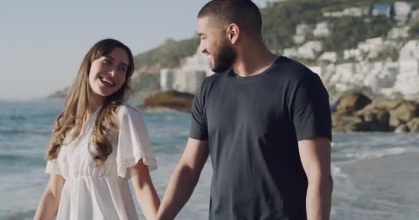 若い幸せなカップルの手を握って一緒にビーチを歩く 陽気なボーイフレンドとガールフレンドがリラックスして海辺を散歩します 海で過ごす自由な夫と妻 — ストック動画