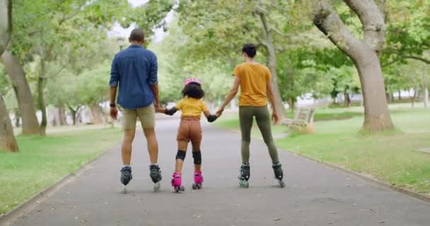 回头看一个无忧无虑的家庭 和他们的女儿一起玩乐 做一个健康的 积极的户外活动 免费情侣们带着孩子戴着粉色头盔 一起在公园里溜冰 — 图库视频影像