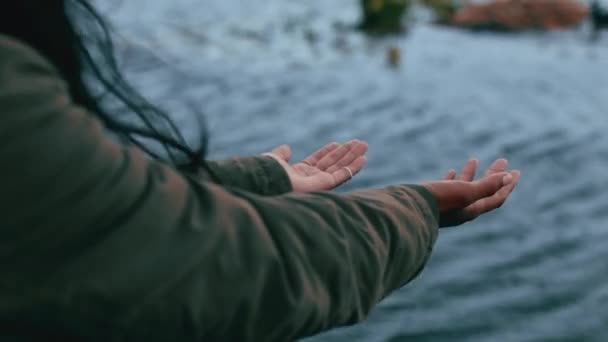 雨を手にして外に一人で立っている無名の女性 雨の中で遊ぶ遊び心のある女性と水滴をキャッチするために腕を上げる レインコートを着て 雨の日を楽しむ女性 — ストック動画