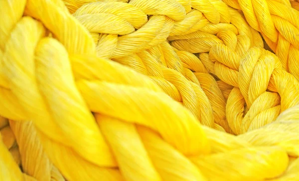 Strong thick braided colorful rope woven and twined. Yellow thick rope macro closeup laying in a heap. Long twisted strong material symbolizes unity, togetherness, and teamwork.