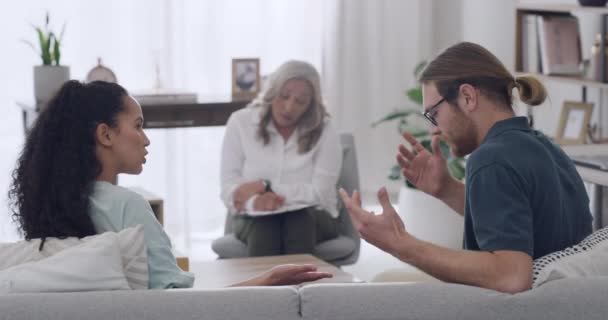年轻的跨种族夫妇坐在沙发上 在与一位成熟的女性治疗师的治疗过程中 在办公室里争论 不快乐的男友和女朋友想办法解决感情问题 — 图库视频影像