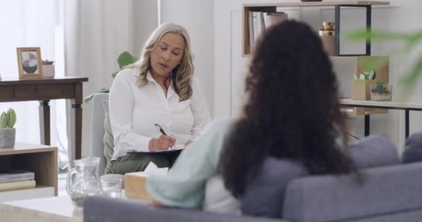成熟した女性心理学者は 患者の話を聞きながら 問題や問題について書いています 治療セッション中に若い患者と彼女の縮小と彼女の感情のバランスに関するアドバイスを得る — ストック動画