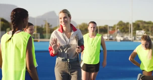 女性ホッケーコーチは選手と戦略を話し 練習中に動機付けをしながらアドバイスを与える スポーツコートで外でトレーニング中にPeの先生を持つ十代の選手の多様なグループ — ストック動画