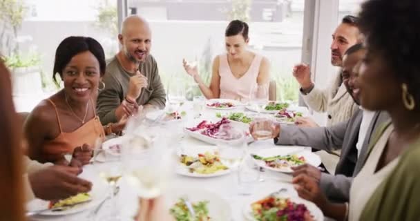 不同的团体在聚会上笑着享用他们的食物和酒 人们一起吃喝着酒 在一个大餐桌前社交 朋友们在家里的饭厅吃午饭 — 图库视频影像