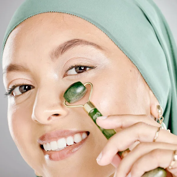 穆斯林妇女笑着 用面部辊在皮肤上 美容师用翡翠滚筒做晨光护肤的日常工作 年轻女性使用瓜沙产品 令肌肤光滑健康 — 图库照片